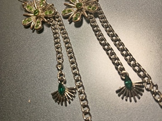 Statement flower earrings with green crystals and chains.